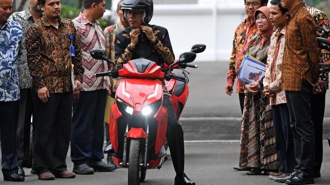 Presiden Joko Widodo mengenakan helm sebelum ANTARA FOTO/Wahyu Putro Amenjajal motor listrik buatan dalam negeri 'Gesits' seusai melakukan audiensi dengan pihak-pihak yang terkait produksi di halaman tengah Istana Kepresidenan, Jakarta, Rabu (7/11/2018). Audiensi tersebut membahas persiapan produksi massal sepeda motor listrik Gesits. [ANTARA FOTO/Wahyu Putro A].