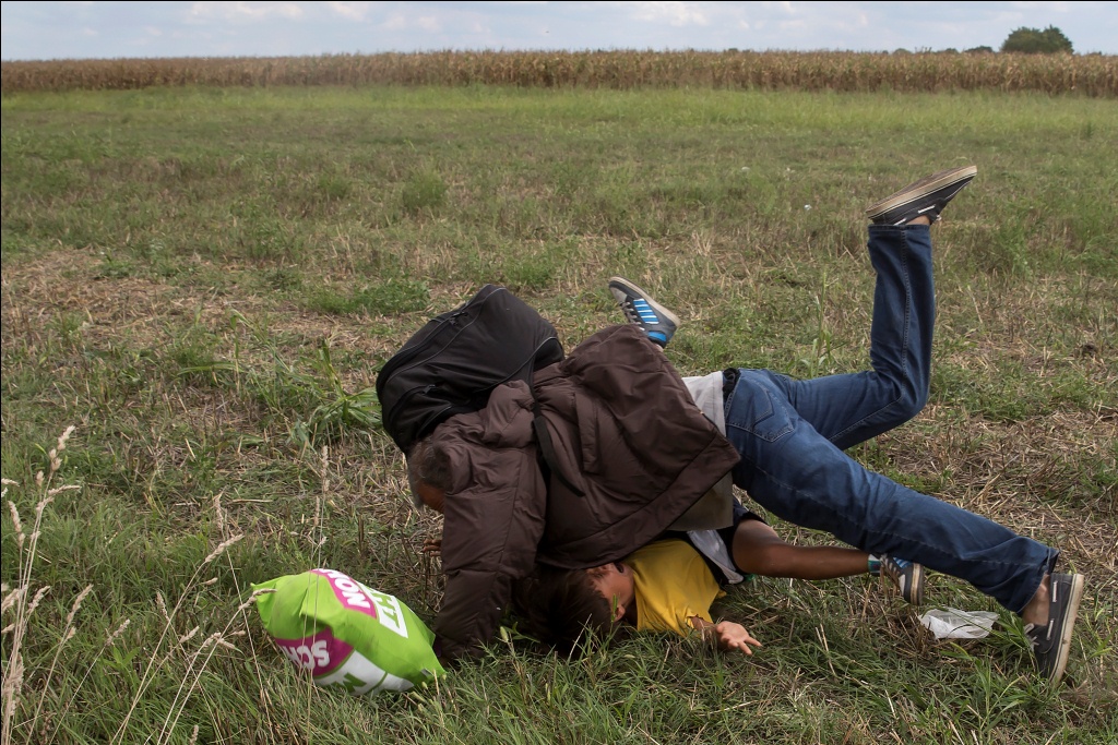 Kamerawati televisi swasta Hungaria menjegal seorang lelaki pengungsi yang menggendong anak kecil. (Reuters/Marko Djurica)