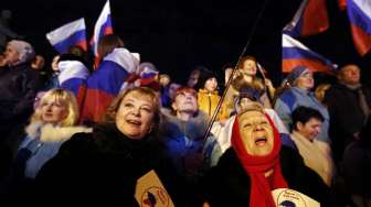 Warga Krimea merayakan hasil pemungutan suara dalam referendum Krimea, di Lenin Square, Simferopol, Minggu (16/3). [Reuters/Thomas Peter]