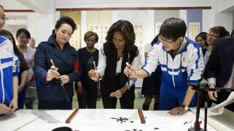 Istri Presiden Cina Peng Liyuan (3kiri) mendampingi Michelle Obama (tengah) saat berkunjung ke kelas tradisional kaligrafi Cina di Beijing, Jumat (21/3). [Reuters/Andy Wong]