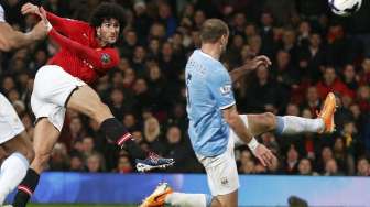 Pemain Machester United Marouane Fellaini melepaskan tembakan melewati pemain Manchester City Pablo Zabaleta dalam laga lanjutan Liga Premier Inggris di Old Trafford, [26/3].[Reuters/Phil Noble]