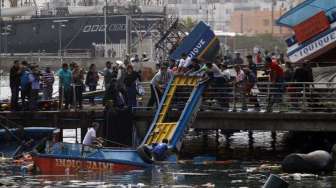 Nelayan memeriksa perahu yang rusak di pelabuhan Iquique, Chile, Rabu (2/4). [Reuters/Luis Hidalgo]