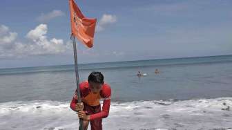 Petugas Badan Penyelamat Wisata Tirtha (Balawista) Kabupaten Badung memasang bendera rambu-rambu larangan berenang menyusul adanya seruan kewaspadaan dampak Tsunami Chili, di Pantai Kuta, Bali, Kamis (3/4). [Antara/Nyoman Budhiana]