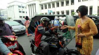 Seorang Polisi Wanita (Polwan) membagikan brosur sosialisasi Undang-undang Lalu lintas kepada pengguna kendaraan bermotor yang melintas di kawasan Jalan Raden Saleh Medan, Sumut, Senin (21/4). [Antara/Septianda Perdana]