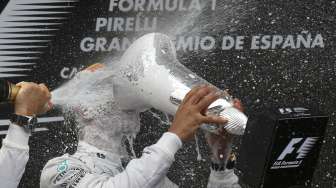 Pebalap Mercedes Nico Rosberg menyemprotkan sampanye ke arah rekan setimnya Lewis Hamilton yang memenangi balap F1 di Catalunya, Spanyol, (11/5). (Reuters/Albert Gea)