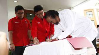 Surya Paloh menandatangani berkas untuk pendaftaran Capres-Cawapres ke KPU di Kediaman Ketua Umum PDI Perjuangan Megawati Soekarnoputri, di Jalan Teuku Umar Jakarta, Senin (19/5). [suara.com/Adrian Mahakam]