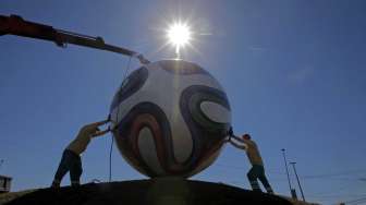 Pekerja memasang bola raksasa di tengah bundaran jalan raya di dekat stadion di Cuiaba, Brazil, Rabu (11/6), menjelang digelarnya Piala Dunia 2014. [Antara/Reuters/Eric Gaillard]