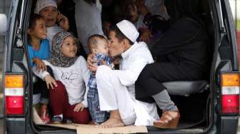 Seorang ayah mencium anaknya sesaat sebelum dilaksanakannya sholat Idul Fitri di Manila, Filipina. (28/7). (Reuters/Erik De Castro)