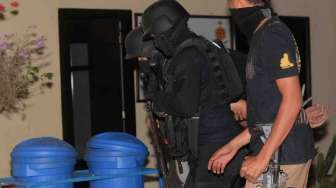 Polisi menggelandang salah seorang dari tujuh terduga anggota Islam State Iraq and Syiria (ISIS) di Kantor Polda Sulawesi Tengah di Palu, Sabtu (13/9). [Antara/Basri Marzuki]
