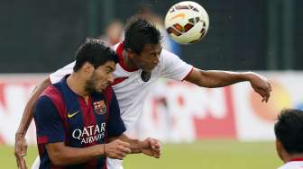 Pemain timnas U-19 Putu Gede bertarung memperebutkan bola di udara dengan pemain Barcelona Luis Suarez [Reuters/Albert Gea]