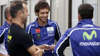 Pebalap Movistar Yamaha, Valentino Rossi (tengah), berdiskusi dengan personel timnya di area paddock Sirkuit Motegi, Jepang, Kamis (9/10/2014). [Reuters/Toru Hanai]