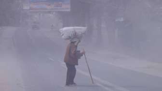 Seorang warga melintas disalah satu jalan yang tertutup debu vulkanik akibat dampak erupsi Gunung Sinabung, Kota Brastagi, Karo, Sumut, Kamis (9/10). [Antara/Tibta Perangin-angin]