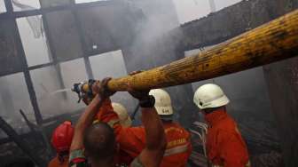 Petugas pemadam kebakaran dibantu warga berusaha memadamkan api yang membakar perumahan padat penduduk di Asrama TNI AD Berlan, Jakarta, Selasa (14/10). [suara.com/Kurniawan Mas'ud]