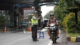 Petugas tol dan polisi lalu lintas membuka dan mengalihkan jalur kendaraan bermotor agar melewati ruas jalan tol Pulo Mas.