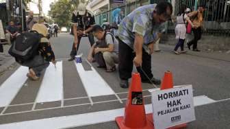 Aktivis dari kelompok Koalisi Pejalan Kaki membuat zebra cross di depan Stasiun Sudirman Jakarta, Jumat (13/3). (Suara.com/Kurniawan Mas'ud)