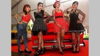 Beberapa orang perempuan bertato berpose di antara jejeran mobil-mobil klasik hot rod yang dipajang di lokasi acara Indonesia Greaser Party 2015, Jumat (10/4/2015), di Plaza Barat Senayan. [Suara.com/Oke Atmaja]