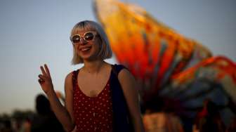 Seorang perempuan berpose di depan kupu-kupu raksasa di Coachella Valley Music and Arts Festival, (12/4). [Reuters/Lucy Nicholson]