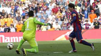 Pemain Barcelona Lionel Messi mencetak gol setelah menaklukkan kiper Valencia Diego Alves (kiri) di Camp Nou. Reuters/Gustau Nacarino