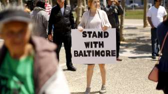 Seorang perempuan di San Francisco, California, memegang poster mendukung aksi unjuk rasa di Baltimore bertepatan dengan peringatan May Day. [Reuters/Robert Galbraith]