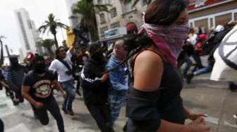 Sejumlah demonstran berlari para peringatan May Day di Mexico City, Meksiko (1/5). [Reuters/Edgard Garrido]