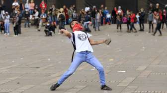 Seorang demonstran melemparkan batu ke arah polisi pada peringatan May Day di Bogota, Kolombia. [Reuters/Jose Miguel Gomez]