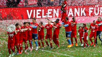 Para pemain Bayern Munich membawa trofi Bundesliga dan merayakannya ke depan penonton di Allianz Arena. Reuters/Michaela Rehle