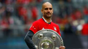 Pelatih Bayern Munich Pep Guardiola memegang trofi Bundesliga. Reuters/Michael Dalder