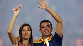 Xavi Hernandez bersama istrinya Nuria Cunillera menyapa fans dalam acara perayaan treble di Camp Nou (8/6) [Reuters/Albert Gea]