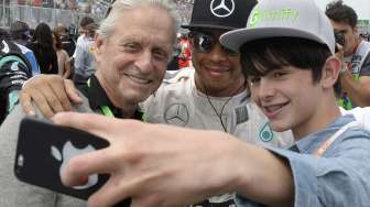 Pebalap Lewis Hamilton berfoto dengan aktor ternama Michael Douglas sebelum balapan. [Reuters/Paul Chiasson]