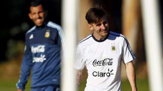 Pemain Argentina Lionel Messi (kanan) tersenbyum saat berjalan di depan rekannya, Carlos Tevez saat sesi latihan. Reuters/Marcos Brindicci