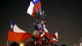 Fans Cile mengibarkan bendera Cile merayakan kemenangan skuatnya atas Uruguay di Santiago (25/6). Reuters/Pablo Sanhueza