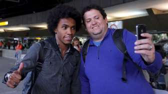 Pemain Brasil Willian meladeni ajakan selfie fansnya saat tiba di bandara internasional Guarulhos, Sao Paolo (28/6). Reuters/Paulo Whitaker