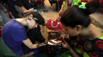 Seorang gadis di Karachi, Pakistan, tengah dibuatkan pola tradisional henna di tangannya, demi menyambut perayaan Idul Fitri, Jumat (17/7/2015). [Reuters/Akhtar Soomro]