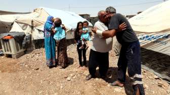 Warga Irak yang tengah mengungsi akibat aksi ISIS di Mosul, saling berpelukan saat merayakan Idul Fitri di kamp pengungsian, di pinggiran Arbil, Jumat (17/7/2015). [Reuters/Azad Lashkari]