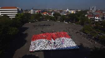 Sejumlah dosen dan mahasiswa memegang potongan kertas yang membentuk bendera Merah Putih, di halaman kampus Universitas Surabaya, Jawa Timur, Senin (17/8/2015). [Antara/Zabur Karuru]