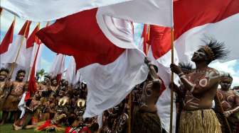 Sejumlah penari berpakaian khas Papua, lengkap dengan sejumlah bendera Merah Putih, tampil dalam acara Peringatan HUT ke-70 RI di Alun-alun Kuala Kencana, Mimika, Papua, Senin (17/8/2015). [Antara/Andika Wahyu]