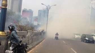 Petugas memadamkan api yang melalap permukiman liar di bawah jembatan layang Kuningan, Jakarta, Rabu (19/8). [Suara.com/Kurniawan Mas'ud]