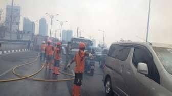 Petugas memadamkan api yang melalap permukiman liar di bawah jembatan layang Kuningan, Jakarta, Rabu (19/8). [Suara.com/Kurniawan Mas'ud]