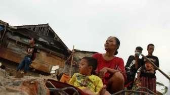 Sejumlah warga Kampung Pulo mencari harta bendanya yang tersisa, di puing-puing bangunan rumahnya yang dibongkar aparat di Jakarta, Kamis (20/8/2015). [Suara.com/Oke Atmaja]