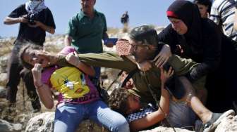 Seorang tentara Israel menangkap seorang bocah Palestina dalam aksi unjuk rasa menentang pembangunan permukiman Yahudi di Desa Nabi Saleh, Tepi Barat, hari Jumat (28/8/2015). [Reuters/Mohamad Torokman]