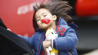 Seorang anak pengungsi bermain dengan balon saat rombongan korban perang menaiki kereta di Nickelsdorf, Austria [Reuters/Leonhard Foeger]