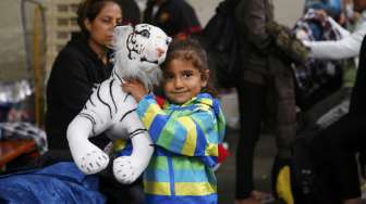 Seorang anak pengungsi memeluk boneka saat orangtuanya mendaftarkan diri sebagai pengungsi korban perang di Munich, Jerman [Reuters/Michael Dalder]