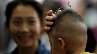 Warga Beijing, baik tua maupun muda mengenakan hiasan rambut berbentuk bunga dan tunas tanaman di jalan Nanluoguxiang, Beijing. [Reuters/Kim Kyung-Hoon]