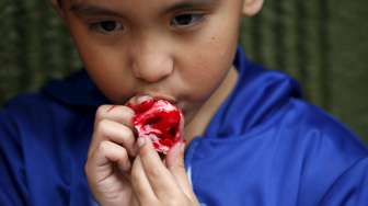 Bocah Meksiko menyantap permen berbentuk mirip hidung manusia di toko pembuat kue ala Zombie di Mexico City, Meksiko. [Reuters/Carlos Jasso]