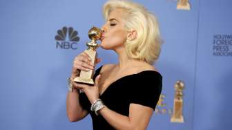 Lady Gaga mencium piala Golden Globesnya, ia menang lewat perannya di film 