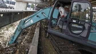 Menggunakan alat berat ekskavator, petugas membersihkan tumpukan sampah akibat hujan lebat di hulu, yang tersangkut di pondasi jembatan Jalan Kalibata Raya, Jakarta, Sabtu (5/3/2016). [Suara.com/Kurniawan Mas'ud]