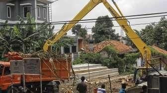 Menggunakan alat berat ekskavator, petugas membersihkan tumpukan sampah akibat hujan lebat di hulu, yang tersangkut di pondasi jembatan Jalan Kalibata Raya, Jakarta, Sabtu (5/3/2016). [Suara.com/Kurniawan Mas'ud]