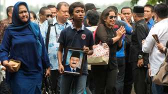 Cucu dari Jacob Nuwa Wea, Evan (tengah), membawa foto Jacob saat jenazahnya tiba di Bandara Halim Perdanakusuma, Jakarta, Minggu (10/4/2016). [Antara/Rosa Panggabean]