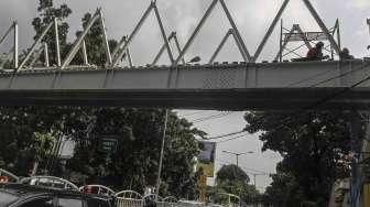 Pekerja menyelesaikan proyek pembangunan Jembatan Penyeberangan Orang (JPO) di Jalan Dr Soepomo, Tebet, Jakarta, Selasa (19/4/2016). [Suara.com/Kurniawan Mas'ud]