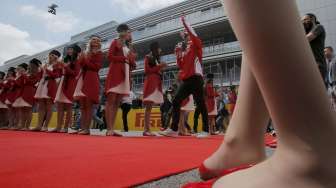 Sebastian Vettel berjalan melintasi karpet merah yang 'dipagari' oleh model-model cantik berpakaian merah-putih, dipadu topi bulu bergaya Cossack warna hitam.[Reuters/Maxim Shemetov]